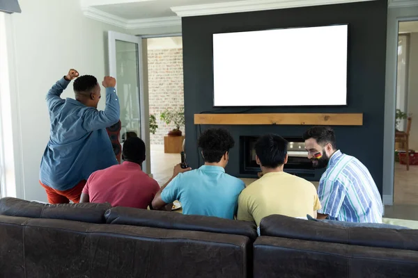週末を自宅で楽しみながらテレビで試合を見ている多人種男性の友人の背面ビュー コピースペース スクリーン テクノロジー 変更されていない 一緒に 社会的な集まり 楽しみ — ストック写真
