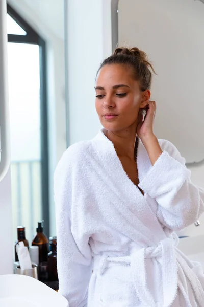 Caucasian young woman wearing white bathrobe at home, copy space. Unaltered, spa, home, relaxation, pampering, detox, body care and wellbeing concept.