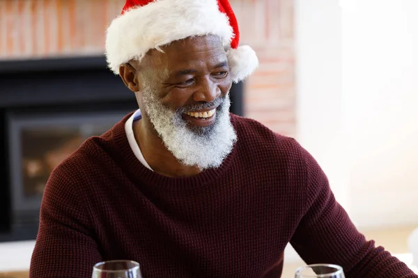 Ανώτερος Αφροαμερικάνος Κάθεται Στο Τραπέζι Χαμογελώντας Και Φορώντας Καπέλο Σάντα — Φωτογραφία Αρχείου