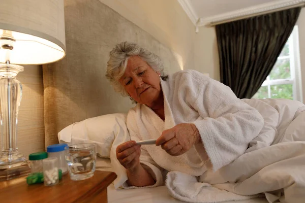 Starsza Kaukaska Kobieta Spędzająca Czas Domu Leżąca Łóżku Patrząca Termometr — Zdjęcie stockowe