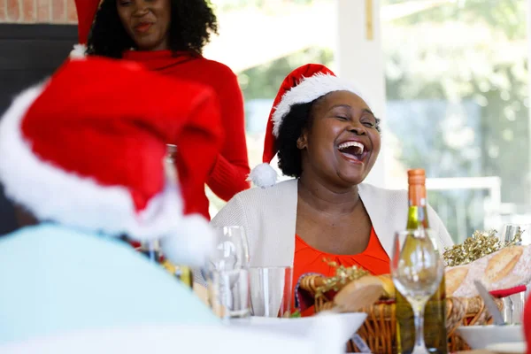 Mujer Afroamericana Mayor Sentada Mesa Sonriendo Vistiendo Sombrero Santa Calidad —  Fotos de Stock
