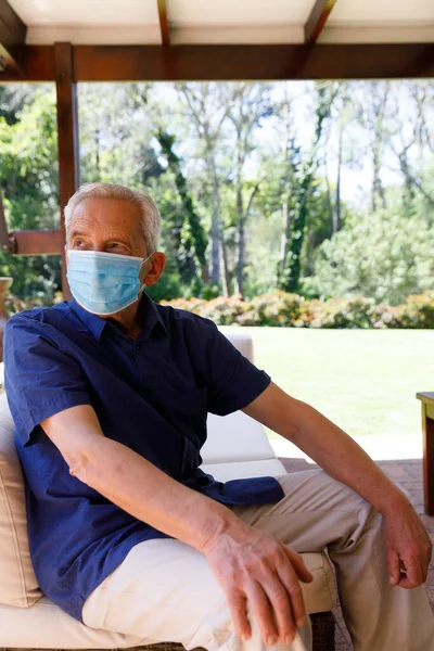 年长的高加索人呆在家里 坐在花园里 戴着面具 望着别处 检疫封闭过程中的分离分离物 — 图库照片