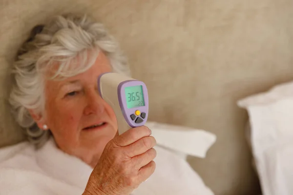 Старшая Белая Женщина Проводит Время Дома Лежа Постели Измеряя Температуру — стоковое фото
