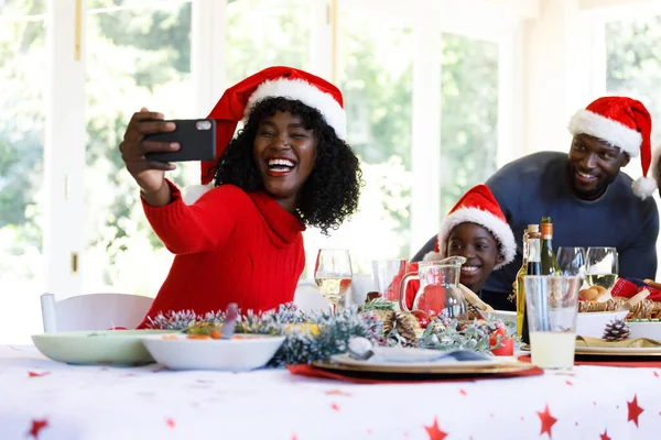 一代又一代的非洲裔美国家庭拿着智能手机自拍 面带微笑 头戴圣诞礼帽 优质家庭时间圣诞庆祝活动 — 图库照片