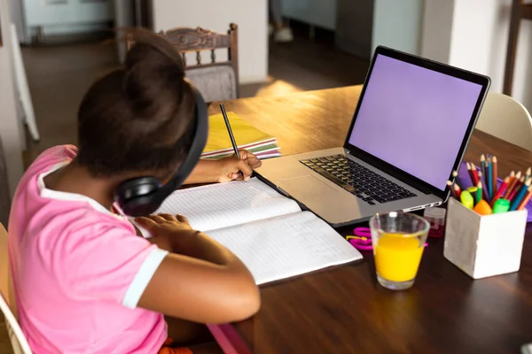 アフリカ系アメリカ人の女の子が自宅でヘッドフォンやノートパソコンを使って学校の仕事をしたり 画面上のスペースをコピーしたり 子供時代 オンライン学習 家庭生活 — ストック写真