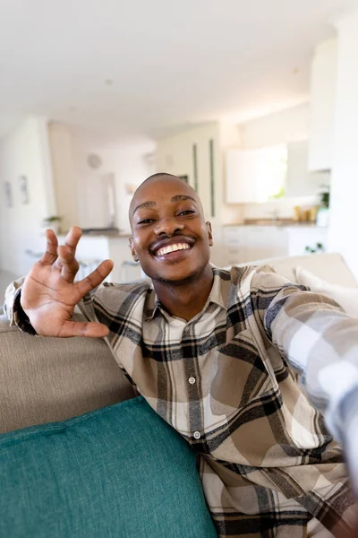 ソファに座っている間 アフリカ系アメリカ人の若い男がジェスチャーやカメラを見て笑顔の肖像画 コピースペース 変更されていない ジェスチャー リラクゼーション ライフスタイルと家庭の概念 — ストック写真