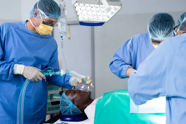 男性患者の外科医の多様なグループは 手術室で麻酔マスクを与えられています チームワーク 医療サービス — ストック写真