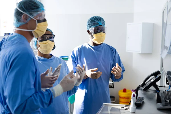不同的外科医生小组在手术室里讨论屏幕上的X光 协同工作 医疗和保健服务 — 图库照片