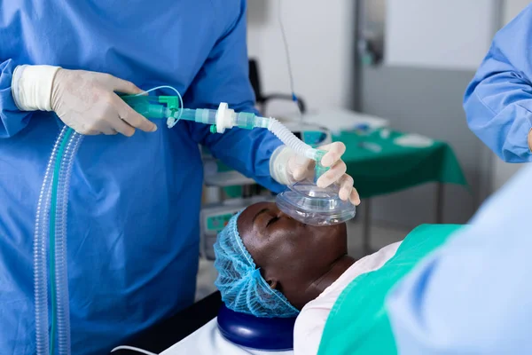手術室でアフリカ系アメリカ人男性の麻酔マスクを与える外科医の中央部 医療サービス — ストック写真