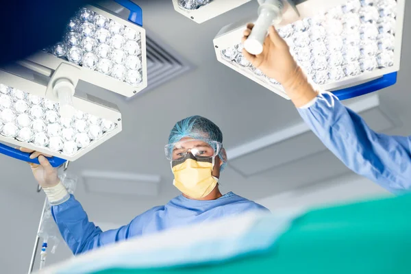 在手术室里 白人男性外科医生与同事一起调整灯光 团队合作 医疗和保健服务 — 图库照片