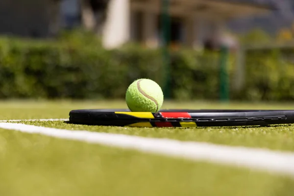 日当たりの良い屋外の芝生のテニスコートの地面にラケットでテニスボール 健康的なライフスタイル スポーツや趣味 — ストック写真