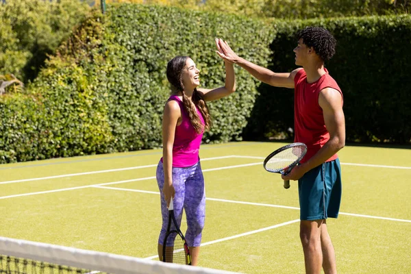 在阳光灿烂的室外网球场上 一对快乐而又多姿多彩的夫妇手握球拍 手握高拳 健康的生活方式 爱好和假期 — 图库照片