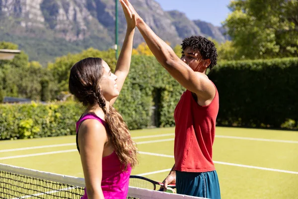 快乐多姿多彩的夫妻手握球拍 在阳光灿烂的室外网球场上高高地打网球 健康的生活方式 爱好和假期 — 图库照片