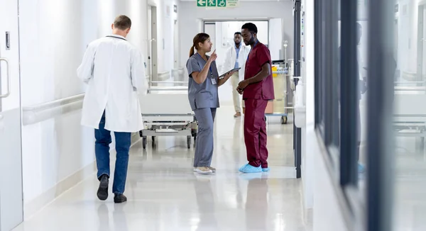 Zróżnicowani Lekarze Płci Męskiej Żeńskiej Stetoskopami Rozmawiający Chodzący Korytarzem Opieka — Zdjęcie stockowe
