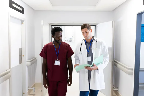 Dos Médicos Masculinos Diversos Mirando Notas Caminando Pasillo Del Hospital — Foto de Stock