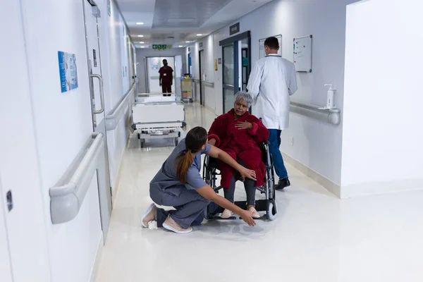 亚洲女医生检查医院走廊中轮椅老年女性病人的腿 医疗和保健服务 — 图库照片