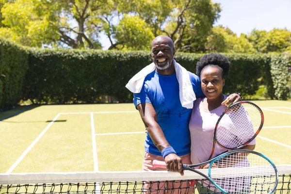 Портрет Счастливой Пожилой Африканской Пары Теннисными Ракетками Обнимающимися Солнечной Травяной — стоковое фото