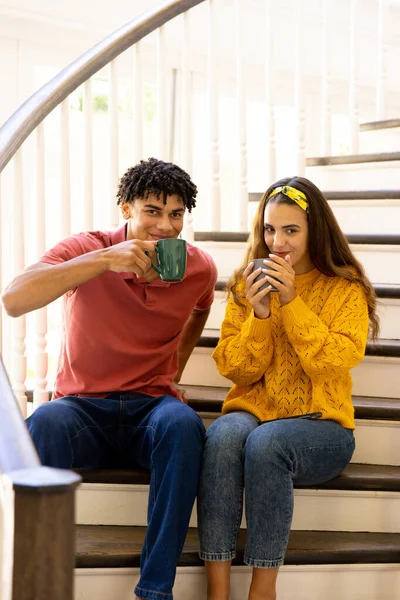 Birasowa Młoda Para Uśmiechnięta Ciesząca Się Kawą Siedząc Schodach Domu — Zdjęcie stockowe