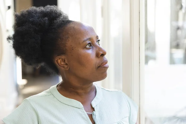Femme Afro Américaine Âgée Réfléchie Debout Regardant Par Fenêtre Maison — Photo
