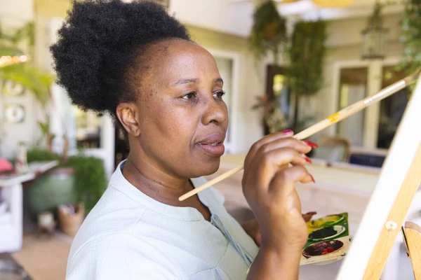 Επικεντρωμένη Ευτυχισμένη Ηλικιωμένη Αφροαμερικανή Που Κρατάει Ζωγραφισμένη Παλέτα Ζωγραφίζοντας Καμβά — Φωτογραφία Αρχείου