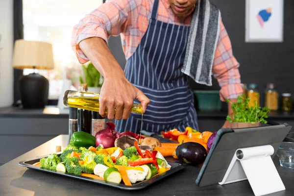 头戴围裙 头戴围裙的男子烹调晚餐 在厨房里倒蔬菜油 保持不变 生活方式 在线烹饪和家庭生活 — 图库照片