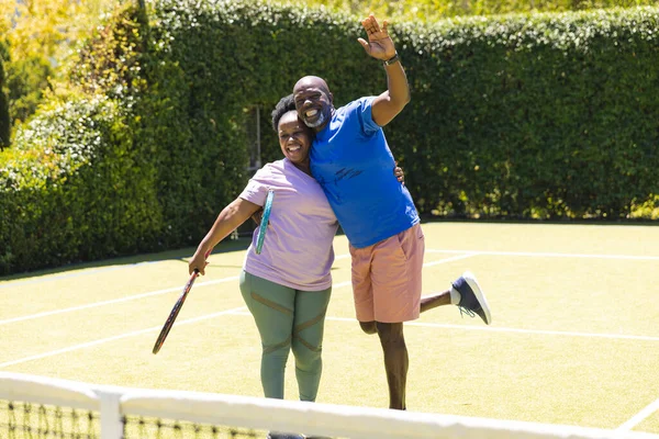Портрет Счастливой Пожилой Африканской Пары Ракетками Солнечном Травяном Теннисном Корте — стоковое фото