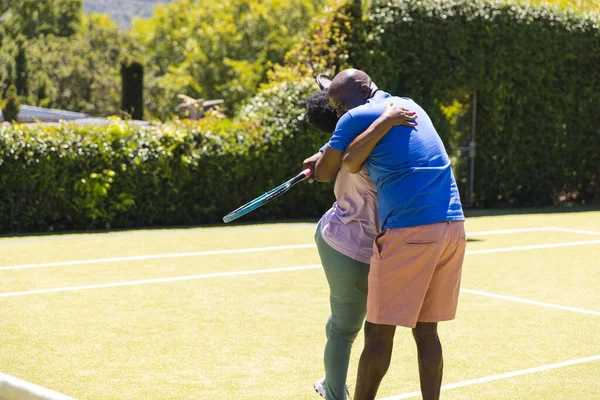 Feliz Pareja Afroamericana Senior Con Raquetas Tenis Abrazándose Soleada Cancha — Foto de Stock