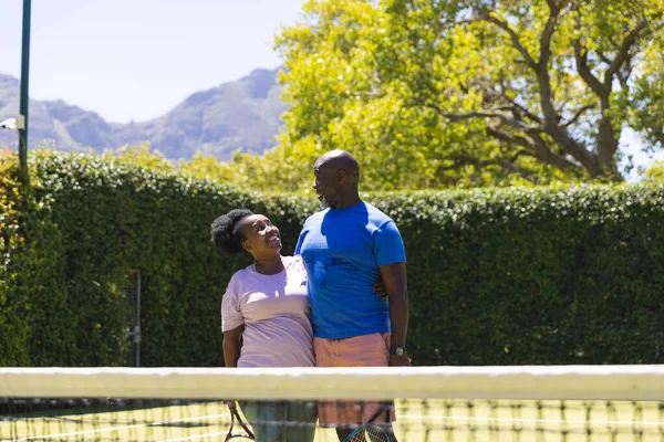 Щаслива Старша Афроамериканська Пара Тенісними Ракетками Обнімається Сонячному Тенісному Корті — стокове фото