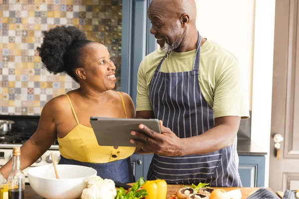 幸せなシニアアフリカ系アメリカ人のカップル一緒に食事を準備し 台所でタブレットを使用します シニアライフスタイル レシピ コミュニケーション 一緒に 食品や国内生活 変更なし — ストック写真
