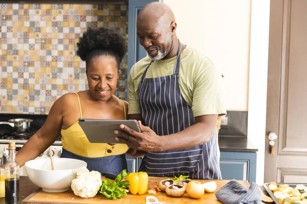 Ευτυχισμένο Ζευγάρι Αφροαμερικανών Που Ετοιμάζουν Γεύμα Μαζί Χρησιμοποιώντας Τάμπλετ Στην — Φωτογραφία Αρχείου