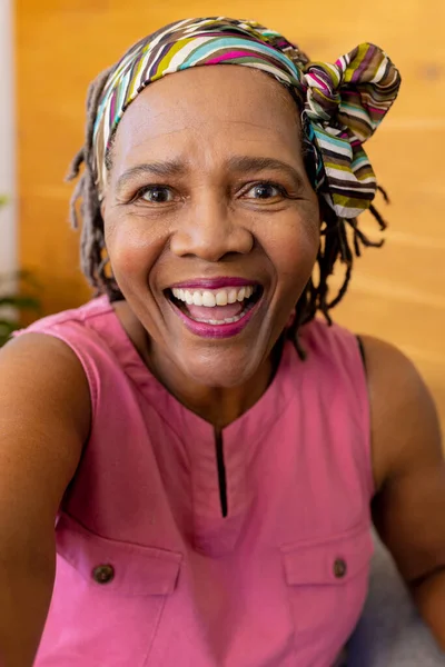 stock image Happy senior biracial woman in headscarf making video call, smiling at home. Senior lifestyle, communication, technology and domestic life, unaltered.