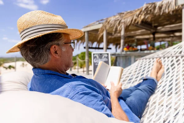 Biały Starszy Mężczyzna Kapeluszu Czytający Książkę Leżący Hamaku Plaży Niezmieniony — Zdjęcie stockowe