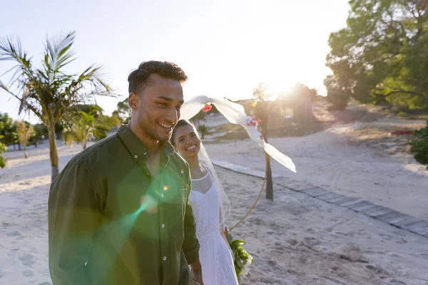 在夕阳西下的婚礼上 一对新婚夫妇在海滩迎着天空散步 面带微笑 复制空间 在一起 目的地婚礼 — 图库照片