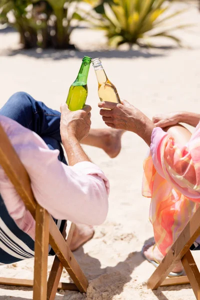 白种人的老两口坐在沙滩上的躺椅上 一边烘焙啤酒瓶 不变的 退休的 度假的 爱情的 一起的 享受的 放松的 手工的 — 图库照片