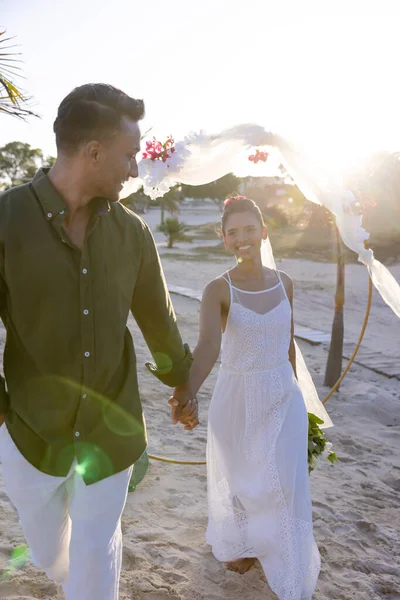 快乐的高加索新婚夫妇手牵着手 在夕阳西下的婚礼上走在海滩上 复制空间 在一起 目的地婚礼 — 图库照片