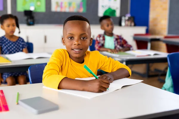 幸せなアフリカ系アメリカ人の小学生の肖像画クラスの机の上に座っている 子供時代と教育 変わらない — ストック写真
