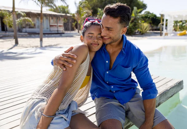 観光リゾートのプールサイドに座っている間 笑顔の白人の若い男が彼女を抱きかかえています 変更されていない 一緒に ライフスタイル 楽しみ ビーチ ロマンス 夏のコンセプト — ストック写真