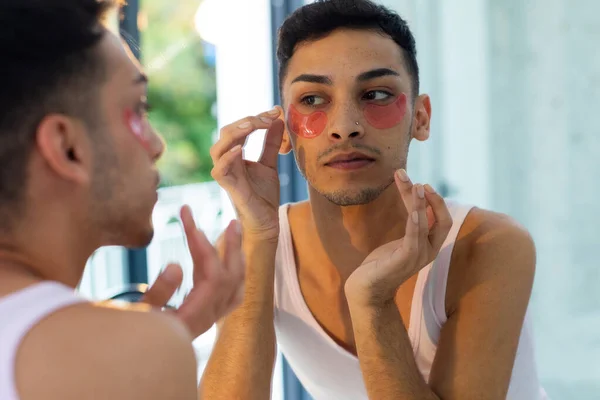 Hombre Transgénero Birracial Mirándose Espejo Aplicando Parches Debajo Los Ojos —  Fotos de Stock