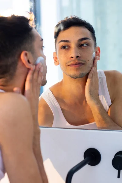 快乐的跨性别男人看着镜子 在浴室涂上护肤霜 自我照顾 生活方式和家庭生活 — 图库照片