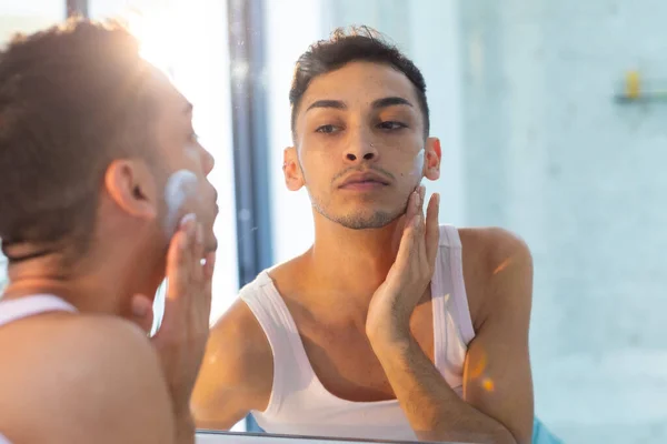 鏡を見てバスルームで顔クリームを適用する出生トランスジェンダーの男 セルフケア ライフスタイル 国内生活 変わらない — ストック写真