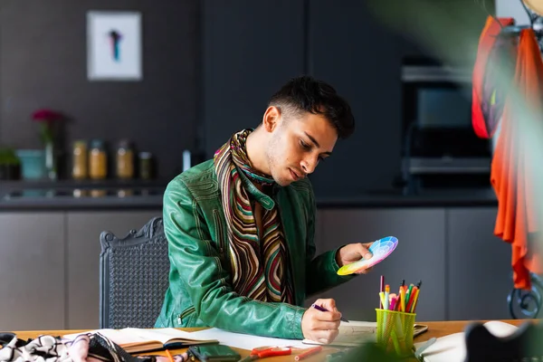 Biracial Transgender Projektant Mody Siedzi Przy Biurku Trzymając Paletę Kolorów — Zdjęcie stockowe