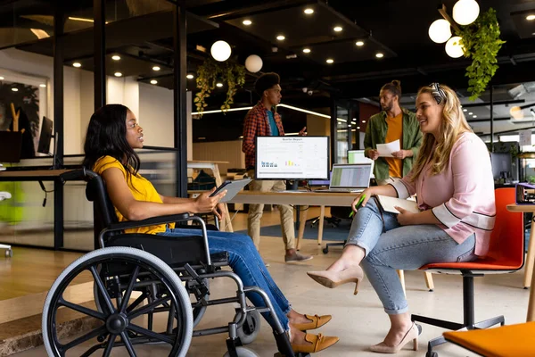 stock image Diverse female colleagues in discussion at casual office meeting. Casual office, teamwork, disability, inclusivity, business and work, unaltered.