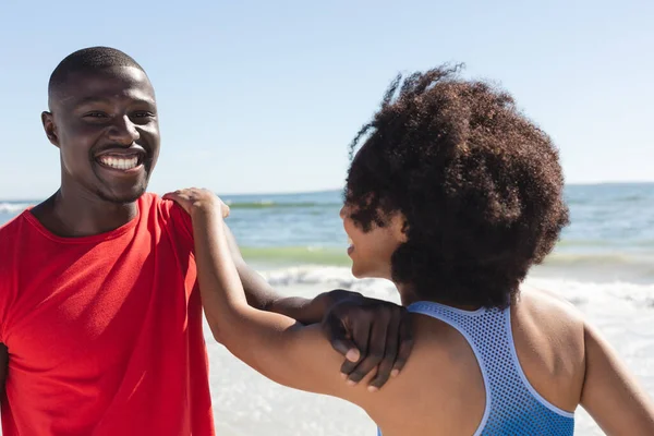 幸せな アフリカ系アメリカ人のカップルの運動に適合し ストレッチや日当たりの良いビーチで笑顔 健康的なライフスタイル フィットネス 自由な時間と休暇 変更なし — ストック写真