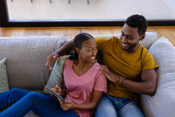 快乐的非洲裔美国夫妇在家里的沙发上笑着拥抱 生活方式 爱情和家庭生活 未经调整的 — 图库照片