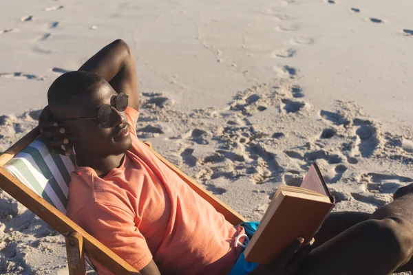 Happy African American Man Sunglasses Sitting Deckchair Reading Book Sunny — Stock Photo, Image