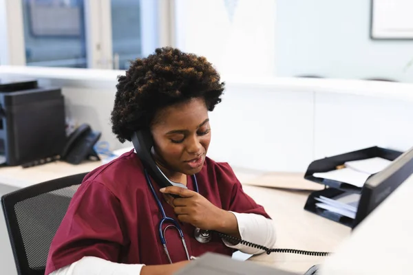Önlük Giyip Steteskop Kullanan Hastanede Telefonla Konuşan Afrikalı Amerikalı Kadın — Stok fotoğraf