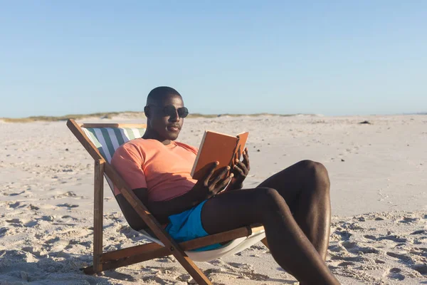 Felice Uomo Afroamericano Occhiali Sole Seduto Sulla Sedia Sdraio Libro — Foto Stock