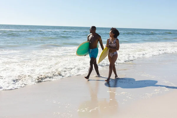Mutlu Formda Afro Amerikan Çift Deniz Kıyısında Sörf Tahtası Taşıyor — Stok fotoğraf