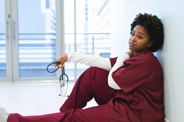 Una Dottoressa Afroamericana Stanca Vestita Camice Seduta Piano Terra Nel — Foto Stock