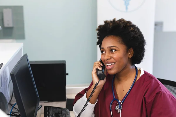 頭蓋骨と聴診器を身に着けて病院で電話で話す幸せなアフリカ系アメリカ人女性医師 コミュニケーション 医療と仕事 変更なし — ストック写真